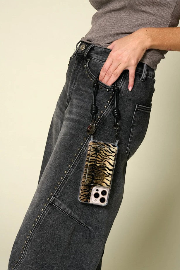 Petra Karthaus black leather knotted wristlet phone lanyard with tiger print card holder attached to a phone.