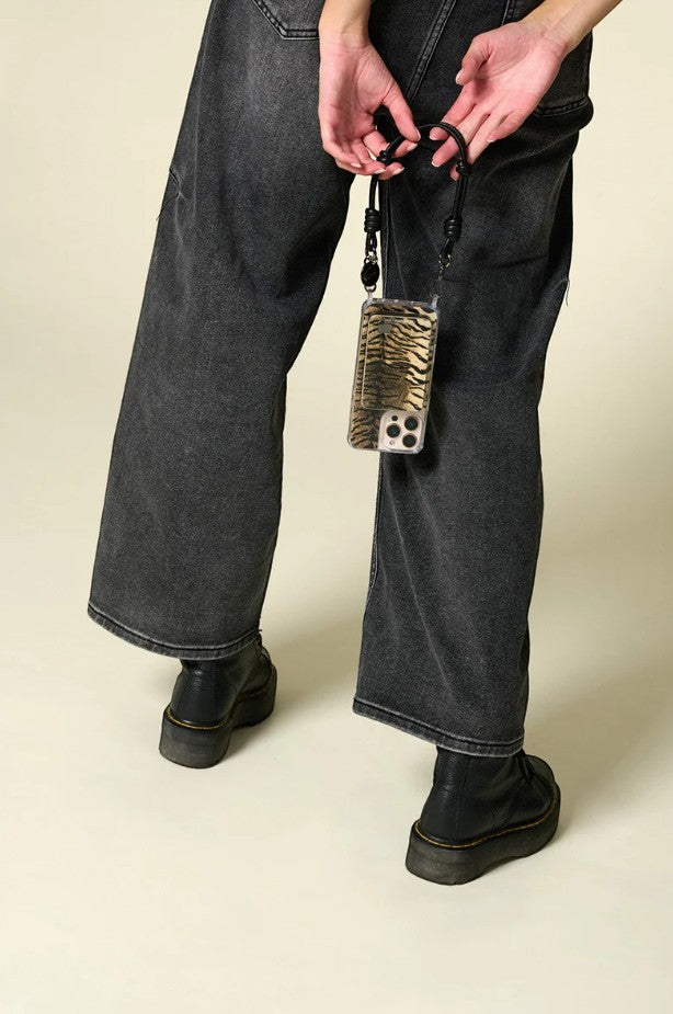 Petra Karthaus black leather knotted wristlet phone lanyard with tiger print phone case attached.